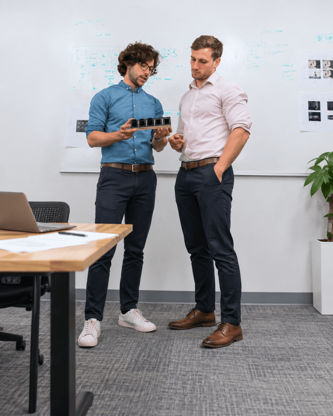 Photo — two colleagues reviewing a prototype in front of a whiteboard